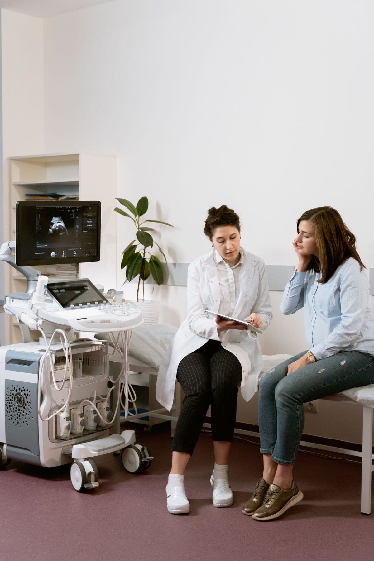 A clinician and a patient talking together in a calm, sunlit exam room