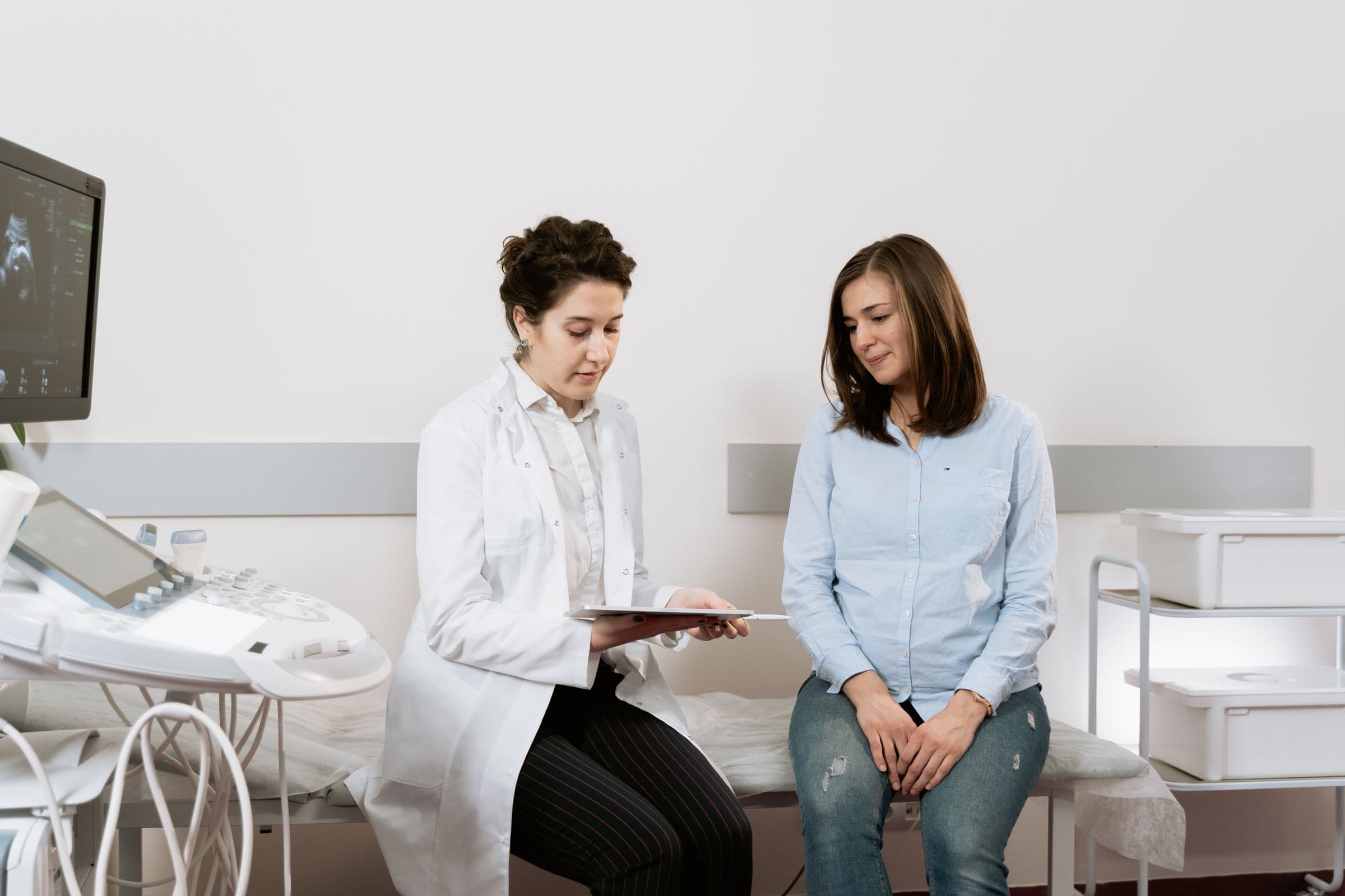 A physician going over results on a tablet with a patient in a bright exam room