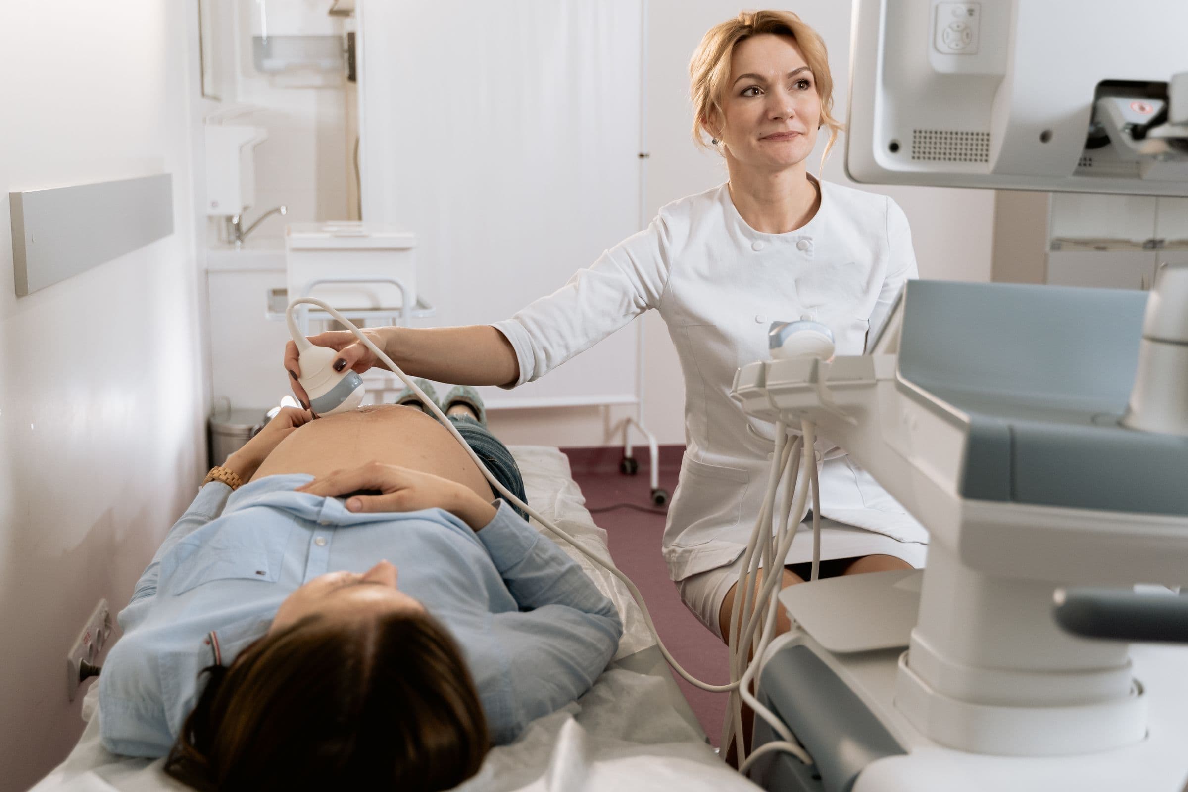 A smiling clinician performing a prenatal ultrasound for an expectant mother