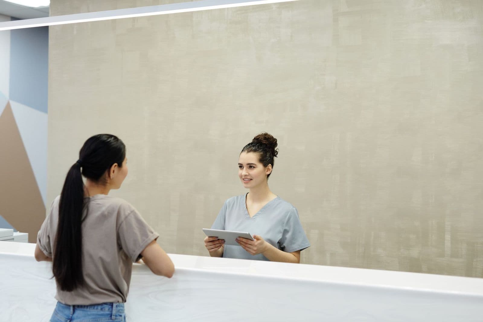 A friendly receptionist welcoming a patient at a clinic front desk
