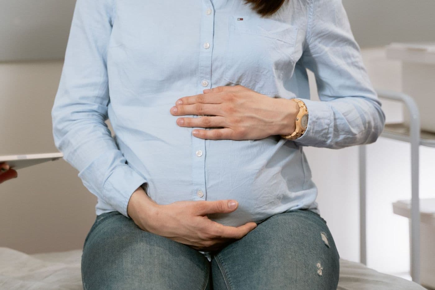 An expectant mother resting her hands on her belly during a visit