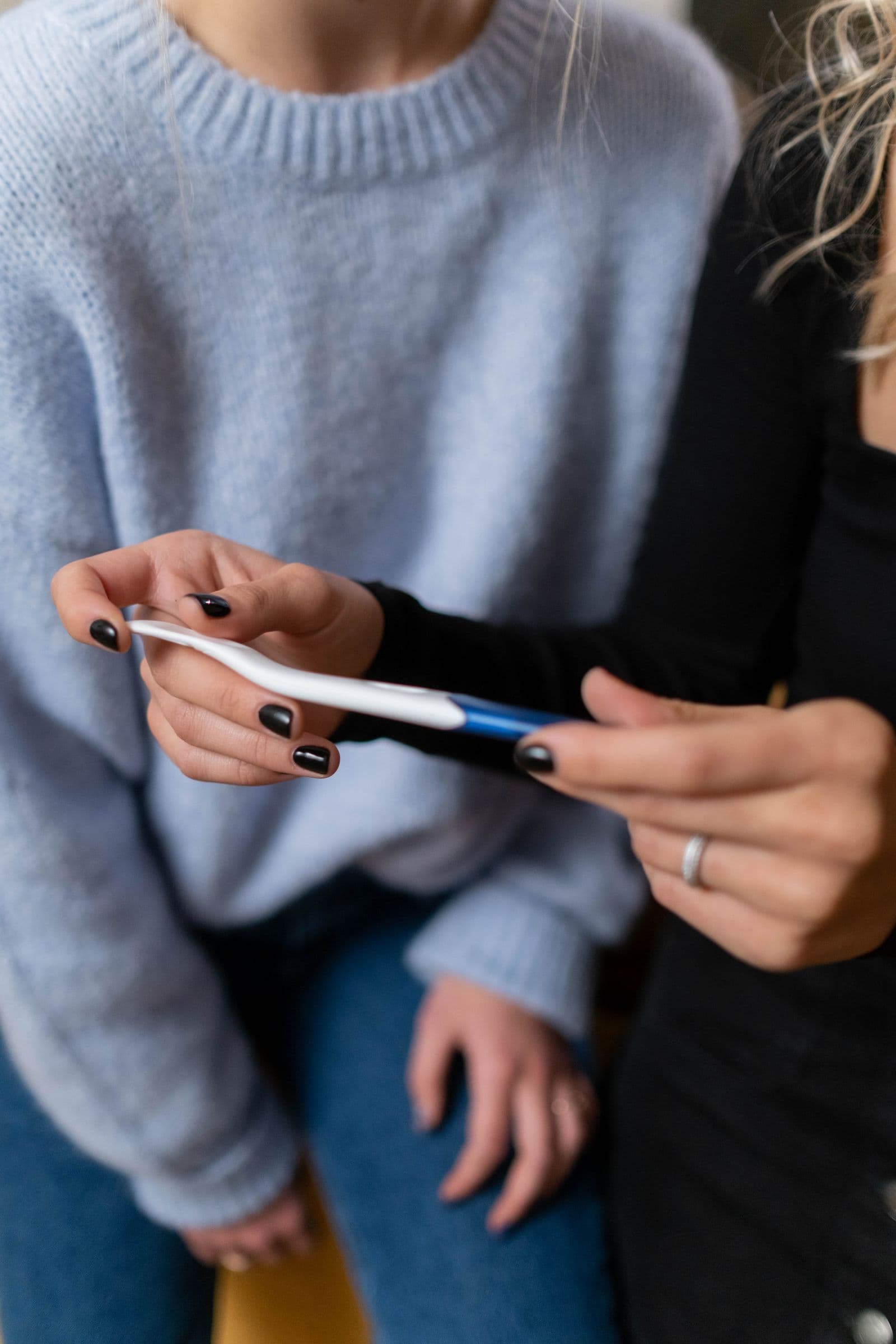 Two young women holding a pregnancy test together
